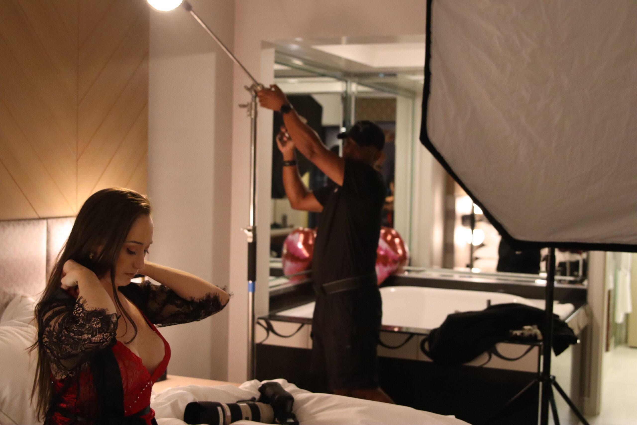 Las Vegas based highly published boudoir photographer Deaqon James adjusts his Neewer Vision5 strobe light while the subject adjusts her lingerie