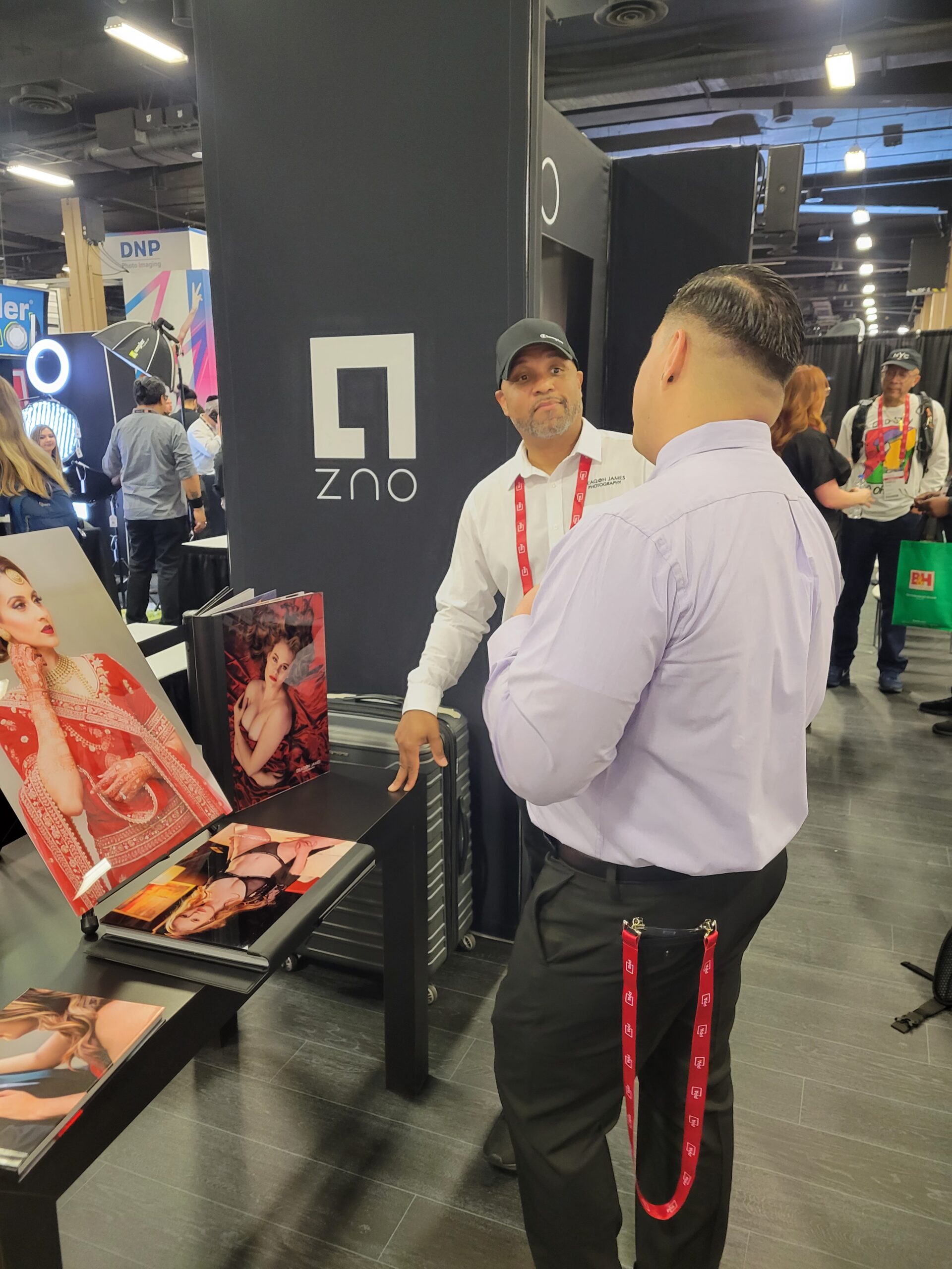Deaqon James discussing business at the ZNO booth with a photographer at Imaging USA